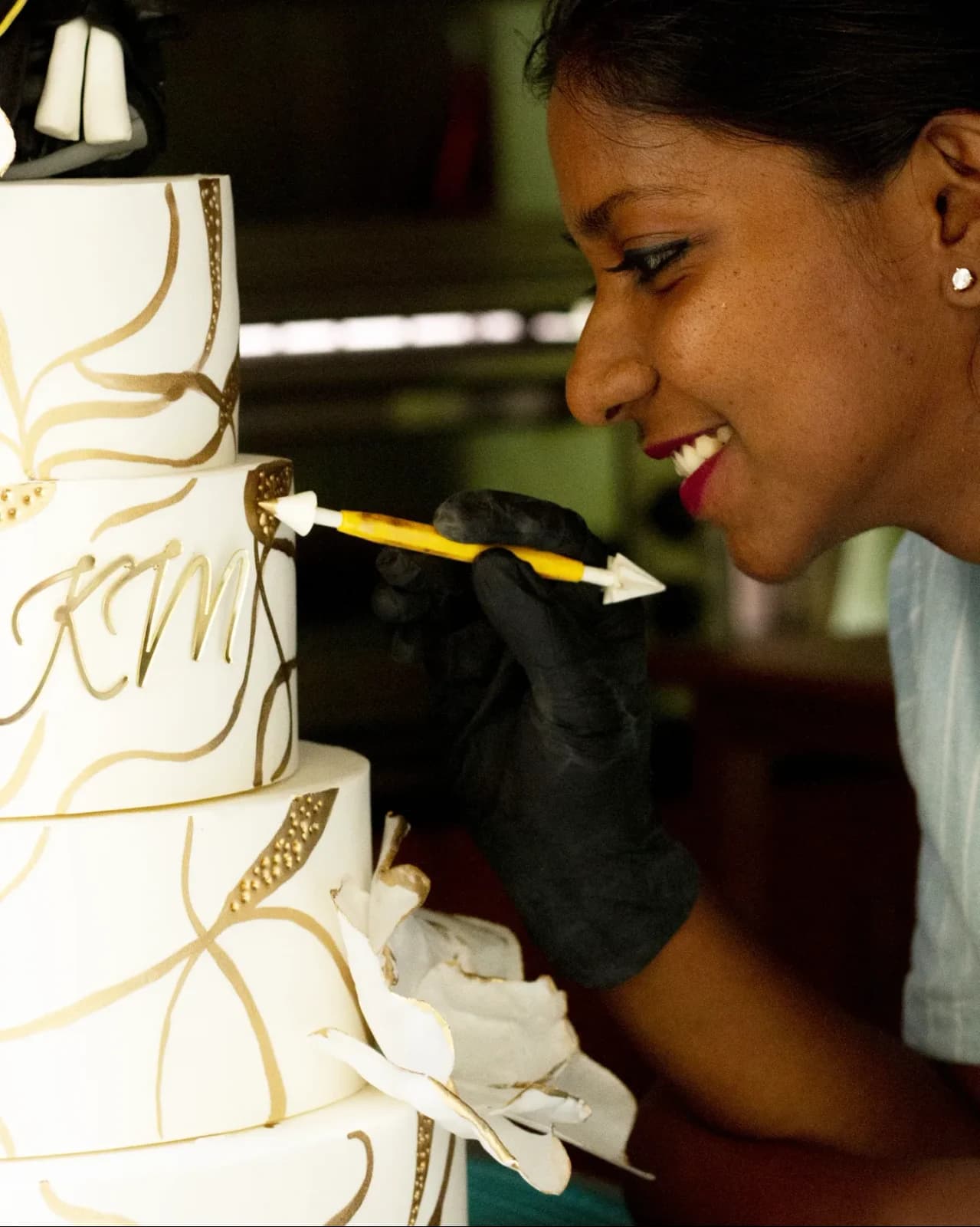 Mridula adding gold details to a white tiered cake