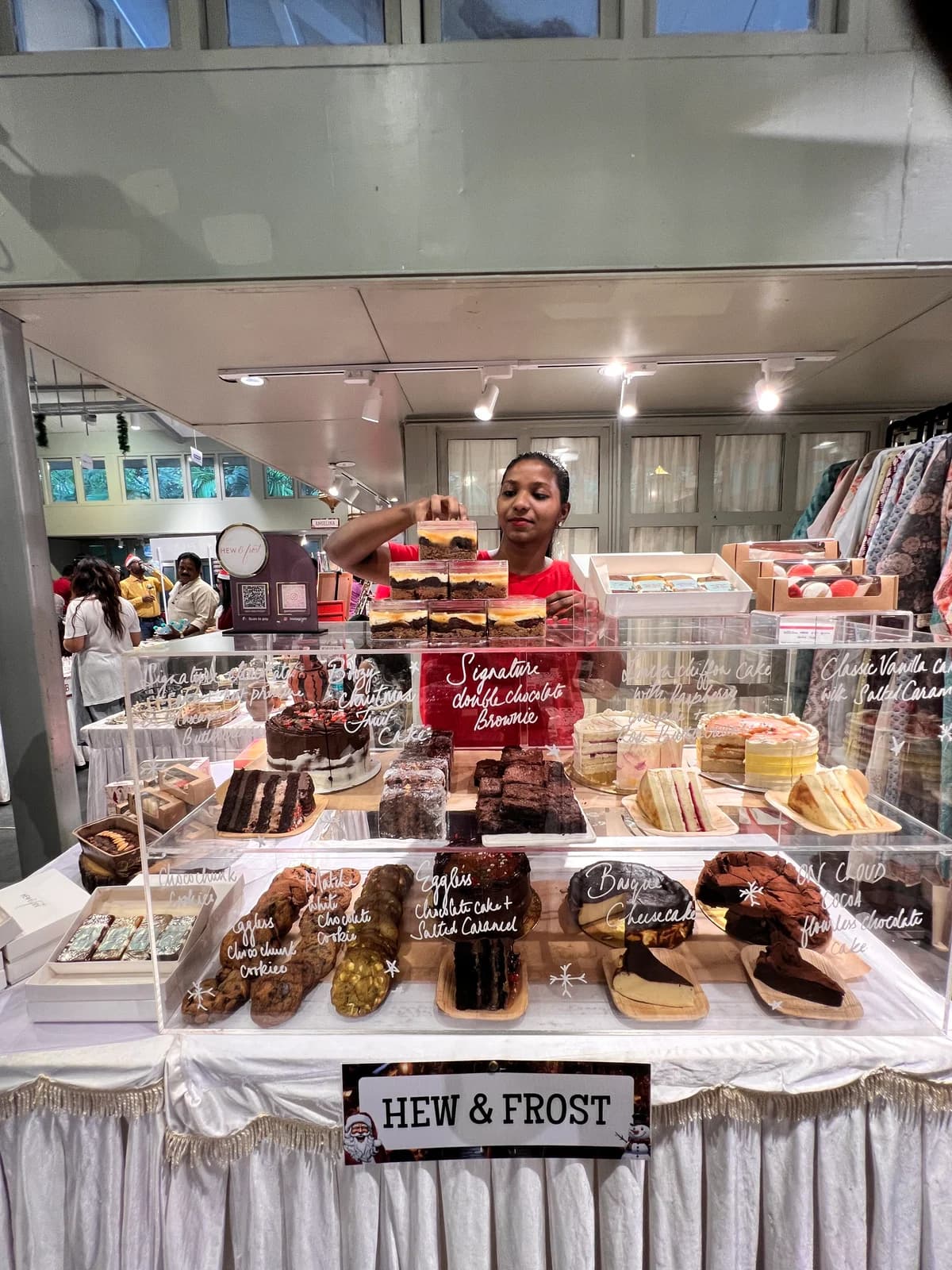 Mridula arranging brownies and cakes at a Hew & Frost pop-up counter