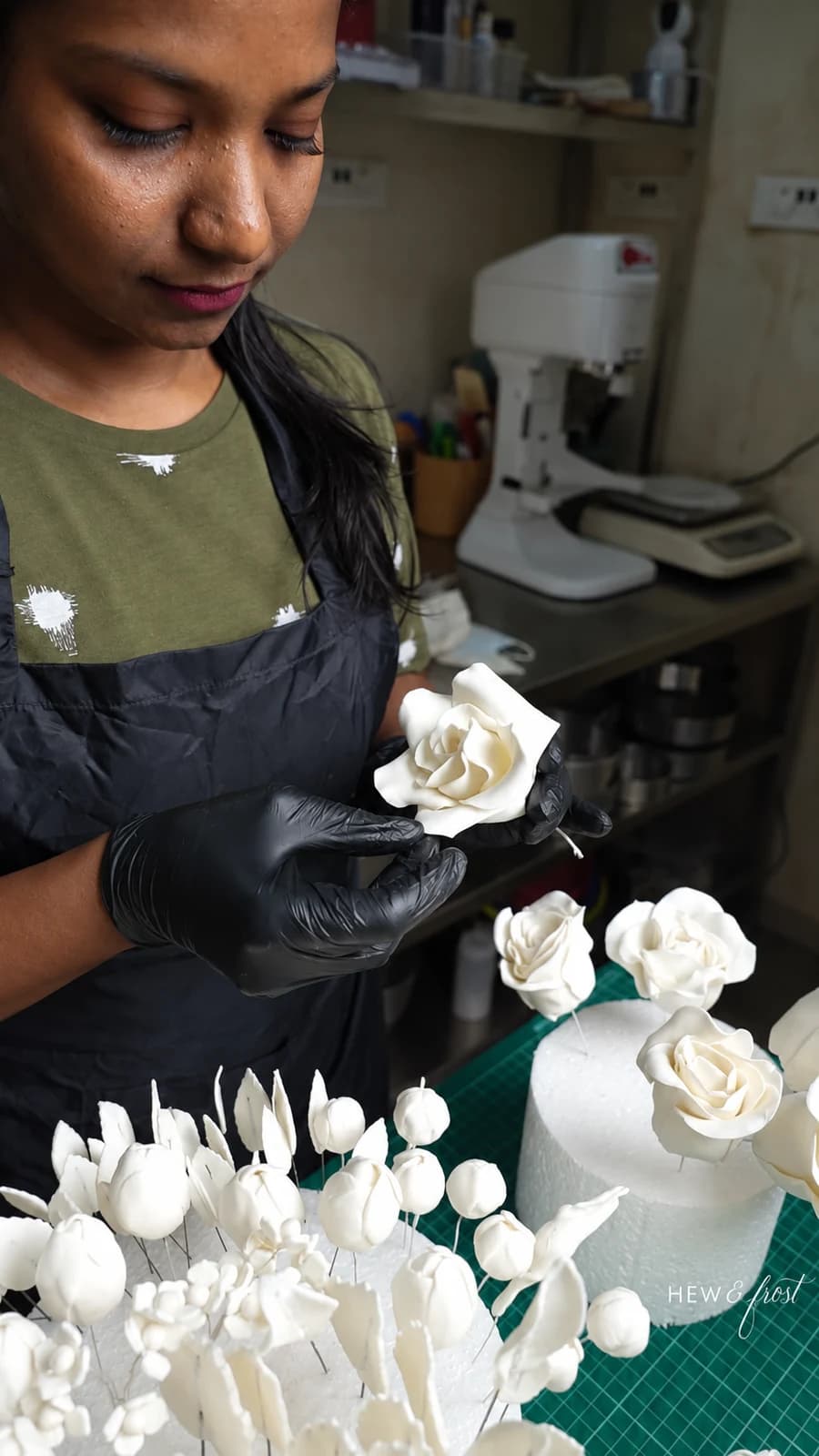 Mridula carefully shaping a white sugar rose at her workbench