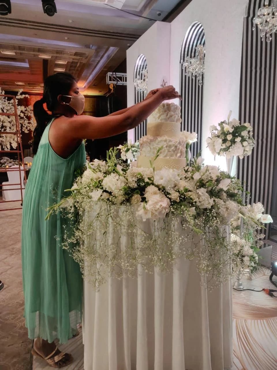 Mridula adding the final details to a white tiered wedding cake